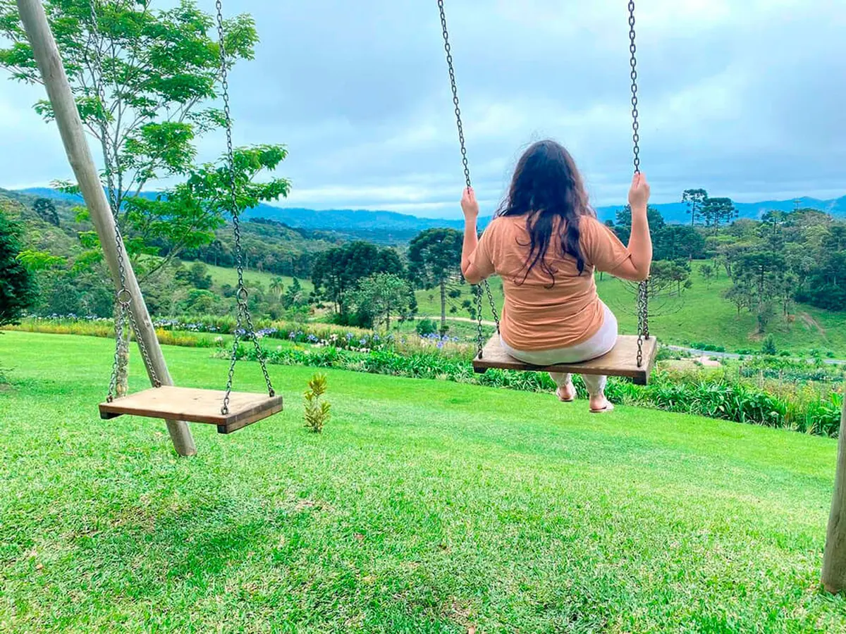Mulher sentada no balanço, contemplando o vale