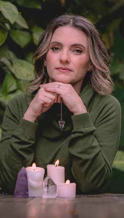 Retrato de Karla Flores com velas, cristais e um pêndulo
